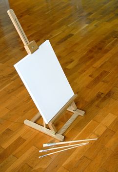 Easel with white canvas on brown parquet indoor