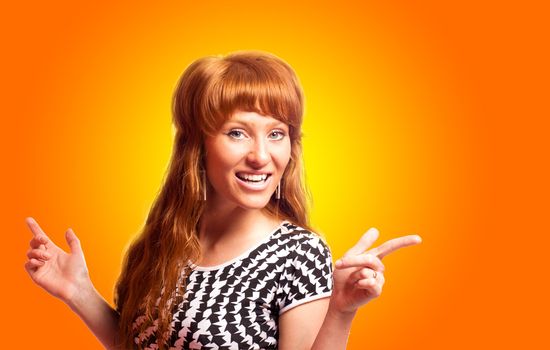 Redhead woman pointing up with smile over orange background
