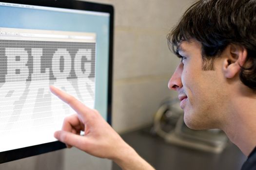 A young main pointing at a computer screen that reads BLOG in the web browser window.  