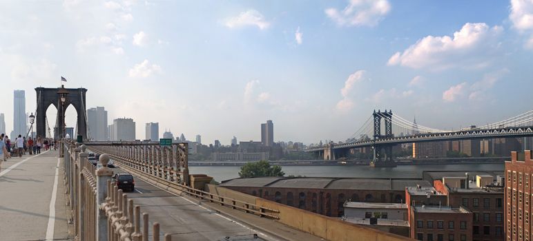A panoramic image of the New York City skyline including the Brooklyn bridge the Manhattan bridge with the Empire State building in the far distance.