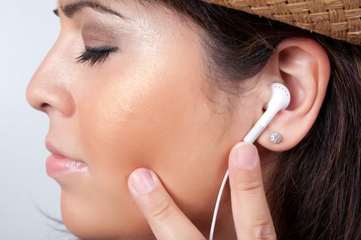 An attractive Hispanic woman listening to and getting into the music playing through her stereo earbud headphones. 