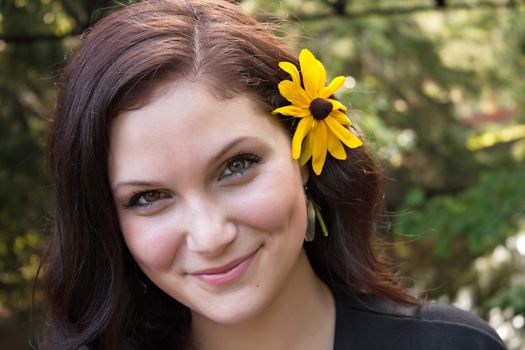 An attractive young woman wearing a black eyed susan wildflower in her hair.