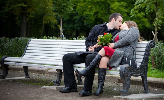 Young Couple Kissing sitting on bench in park