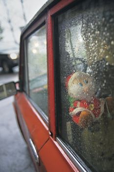 Dwarf toy viewed through car window while raining
