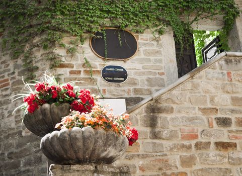 Exterior hotel and resturan sign in a stone wall with flower 