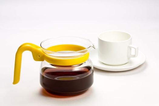 A transparent teacup with yellow handle and black herbal tea  white cup