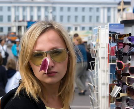 The young woman measures sun glasses near a street rack