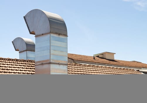 Red tiled roof with chimney on blue sky