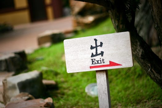 Wooden EXIT sign with chinese word exit and red arrow in park