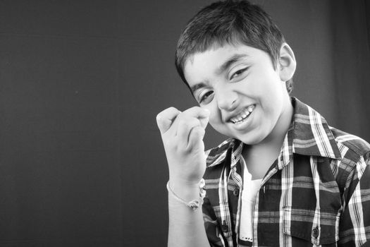 A black & white portrait of a small Indian boy in a joking mood.