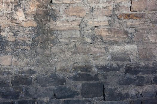 rough sandstone and concrete wall of an old river diversion dam, dark stones indicate high water level