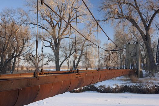 Old abandoned aqueduct (irrigation ditch) suspended across a river in Colorado farmland, winter scenery