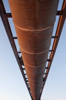 suspended rusty pipe (irrigation ditch aqueduct) shot from below against sky