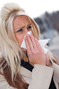 This young woman sneezing into a tissue either has a cold or really bad allergies.