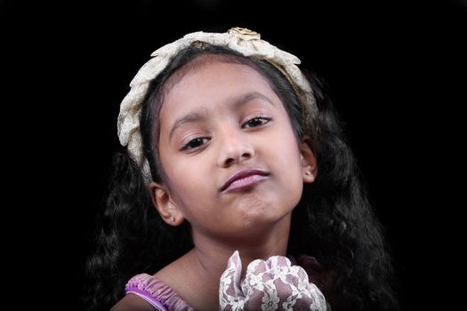 A portrait of a pleading little Indian girl, on black studio background.
