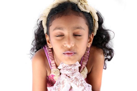A portrait of a cute Indian girl saying a prayer, on white studio background.