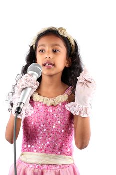 A little Indian girl singing with a mic, on white studio background.