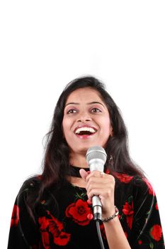 A beautiful talent show host talking to the audience holding a mic, on white studio background.