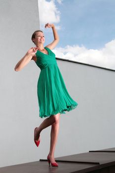 dancing young women in green dress on wind