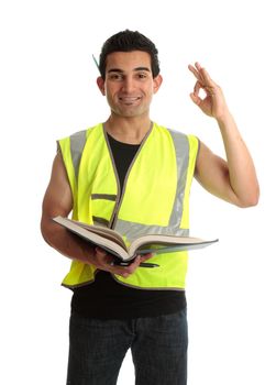 A student apprentice construction worker builder tradesman holding an open book and showing okay sign