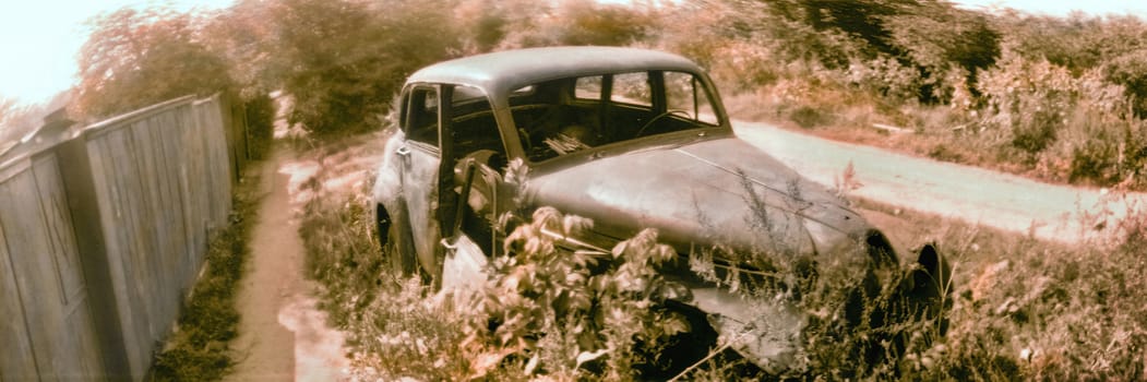 The old deserted automobile at a fence in a countryside