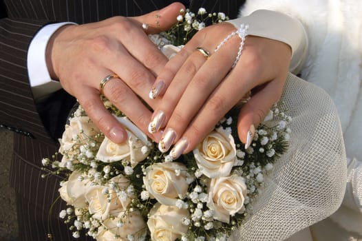 Hands of the groom and the bride put on a wedding bouquet 