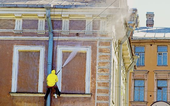 Cleaning service worker washing old building facade