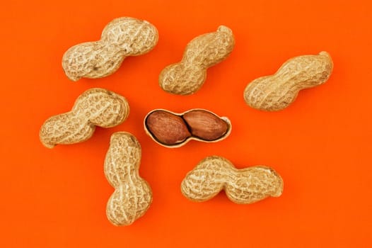 Peanuts on orange background, close up shot.
