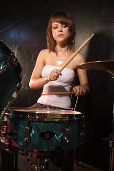 Photograph of a female drummer playing a drum set on stage.