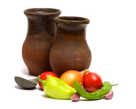 Fresh vegetables, two ceramic bowls and pewter spoon on a white background.