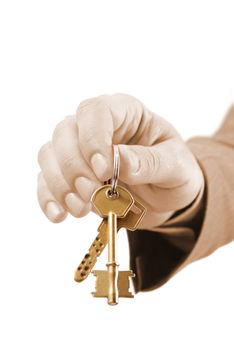 Close-up of a male real estate executive's hand holding two keys. Warm tones picture.
