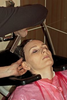 Barber makes a hair-dress to the young brunette