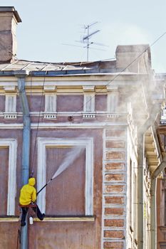 Cleaning service worker washing old building facade