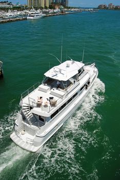 Luxurious white yacht cruising by the miami beach marina on the florida intercoastal waterway on its way to the open ocean.