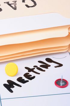 The information on a calendar about meeting with office accessories.