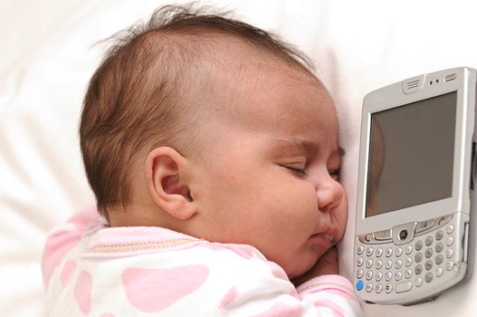 infant baby sleeping next to a mobile phone