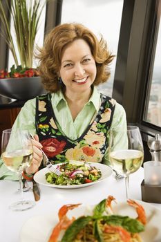 Caucasian mature woman with meal in restaurant smiling.