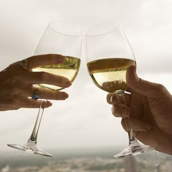 Close up of mature couple's hands toasting white wine.