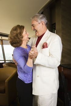 Mature Caucasian couple dancing and laughing.