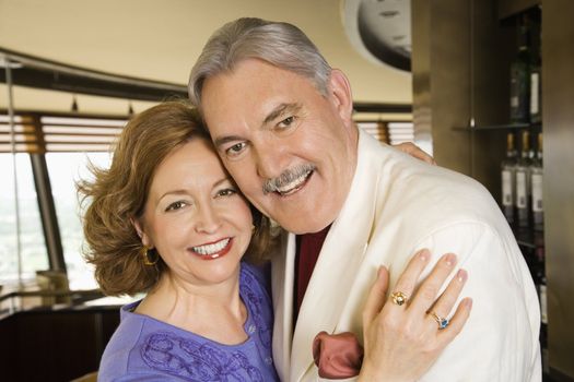 Portrait of mature Caucasian couple embracing and smiling.
