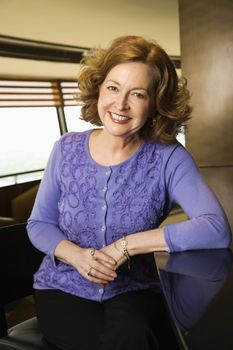 Portrait of smiling middle aged Caucasian woman sitting at otherwise empty bar.