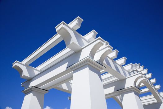 Detail of white arbor against blue sky.