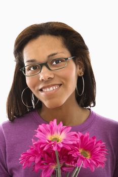 African American mid adult woman wearing glasses holding pink flowers and smiling at viewer.