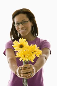 African American mid adult woman wearing glasses holding bouquet of flowers towards viewer.