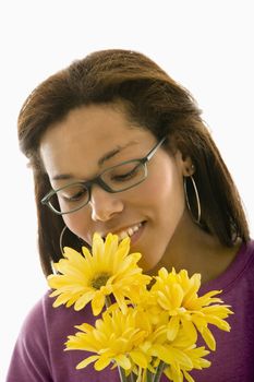 African American mid adult woman wearing glasses smelling bouquet of Gerbera dasies.