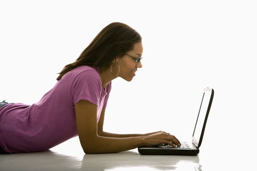 Side view of mid adult African American woman lying on floor using laptop.