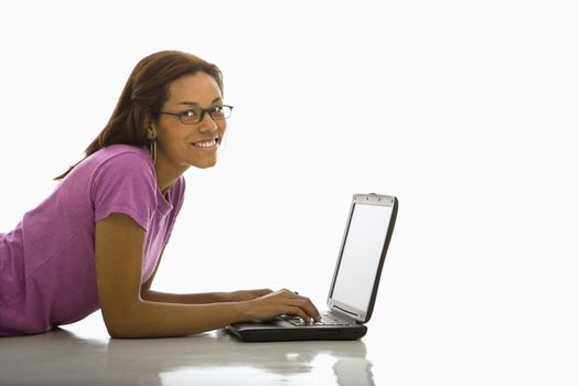 Side view of mid adult African American woman lying on floor using laptop smiling at viewer.