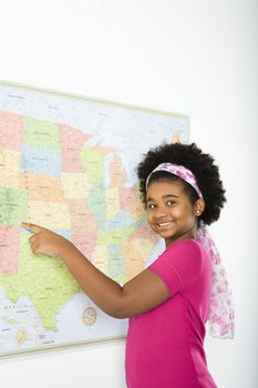 African American girl pointing to map of United States and smiling at viewer.