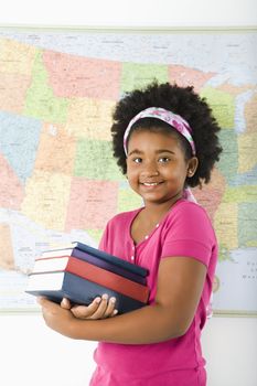 African American girl standing in front of USA map holding stack of books smiling at viewer.