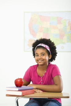 African American girl sitting in school desk smiling at viewer.